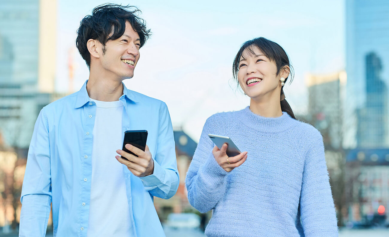 スマートフォンを持って会話する男女